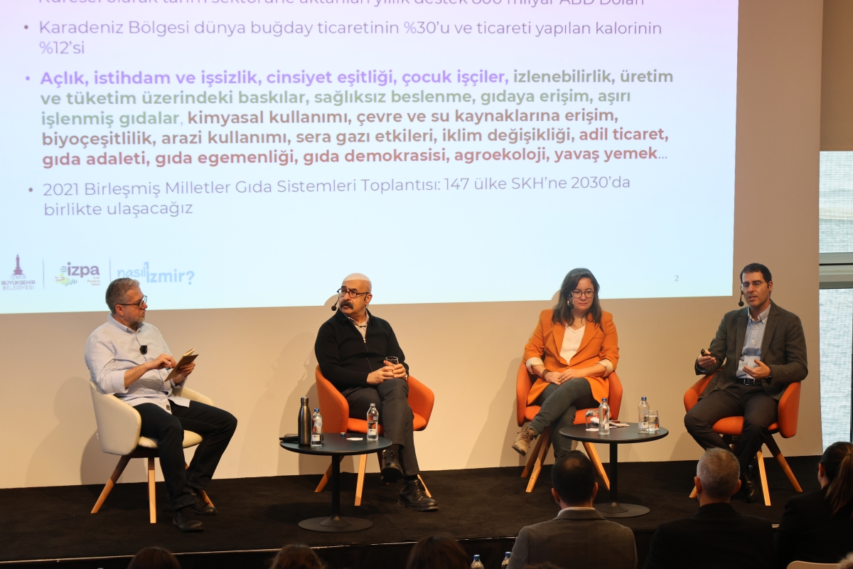Panel konuşmacıları sahnede otururken görülüyor