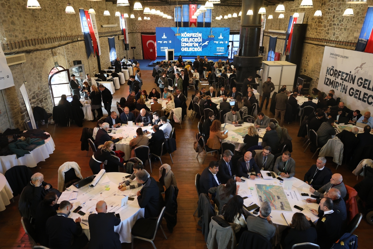 Çalıştay katılımcıları yukarıdan çekilen fotoğrafta masalarda otururken görülüyor