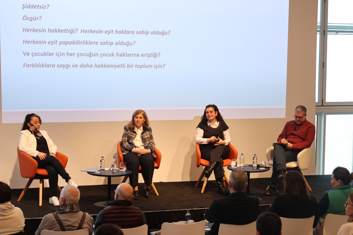 Panelistler ve moderatör sahnede otururken görülüyor